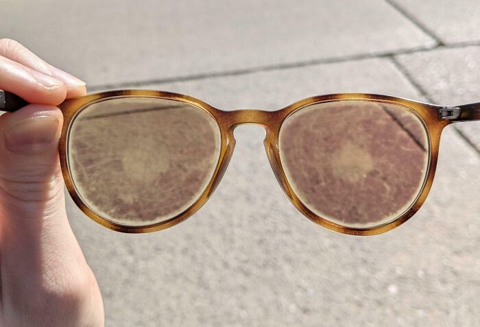 Worn-down glasses showing signs of aging held in hand.
