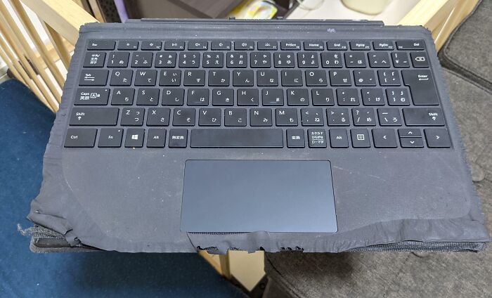 Worn-down laptop with keyboard showing signs of time, highlighting people's belongings aged by use.