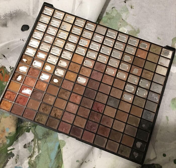 Worn-down makeup palette showcasing the effects of time with faded colors and empty pans.