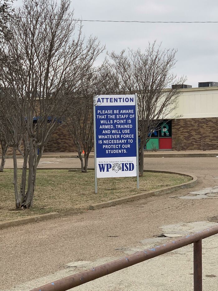 Sign in front of American school stating staff is armed and trained to protect students.