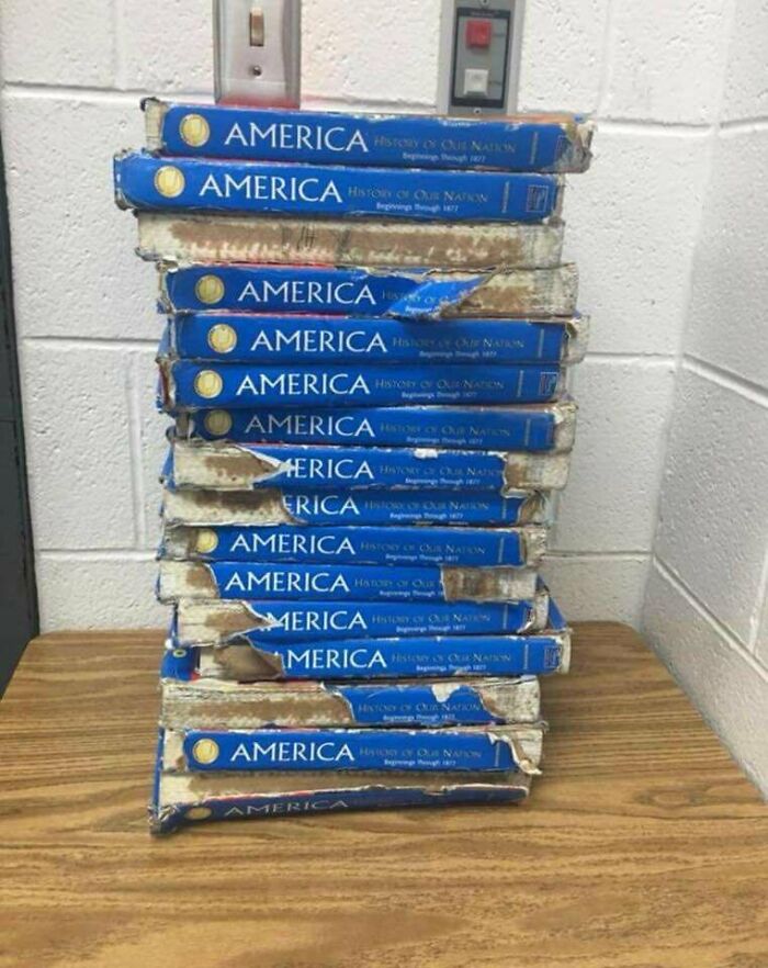Worn American history textbooks on a classroom desk, highlighting school conditions.