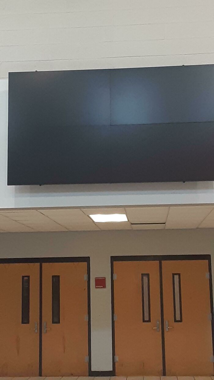 Blank screen above school hallway doors, showcasing American school infrastructure.