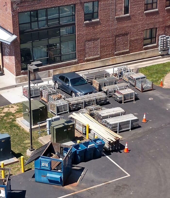 Coche aparcado rodeado de vallas en un patio trasero, mostrando un error de estacionamiento sorprendente.