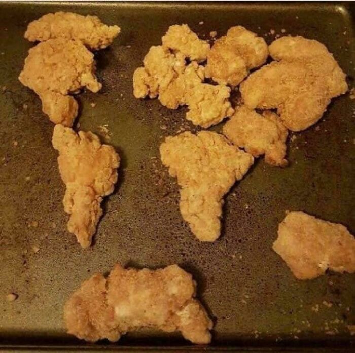 Pieces of fried chicken resembling a world map on a baking tray; nothing interesting here.