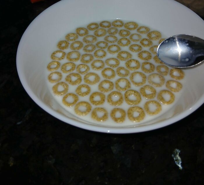 Bowl of cereal in milk, neatly arranged with a spoon beside it.