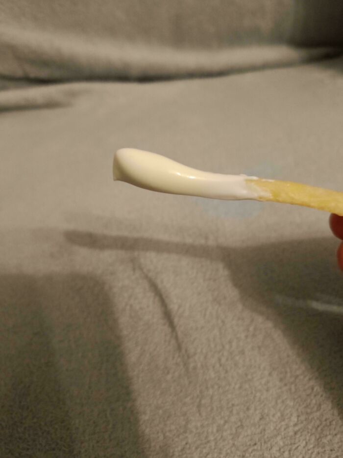 Plain chip with a dollop of mayonnaise on a neutral background.