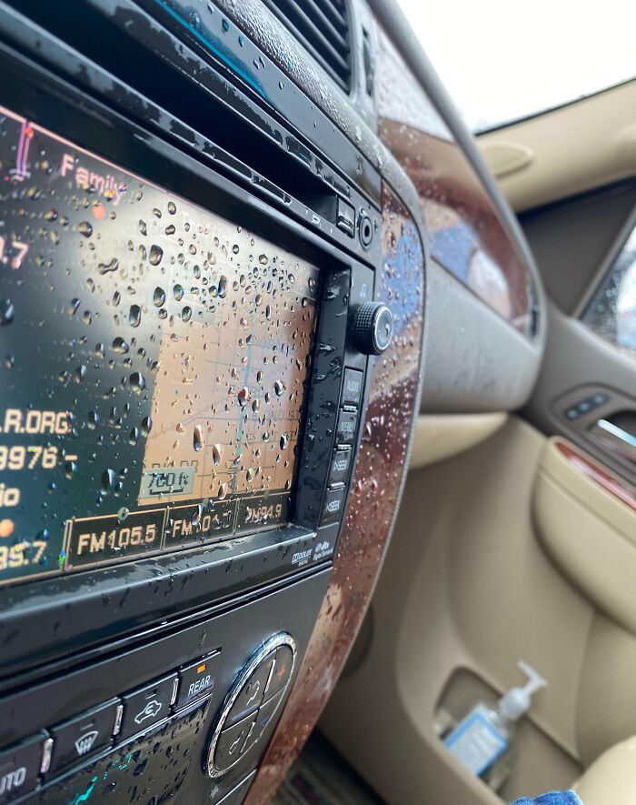 Pantalla de automóvil cubierta de gotas de lluvia, ilustrando error común en el uso de electrónica bajo la lluvia.