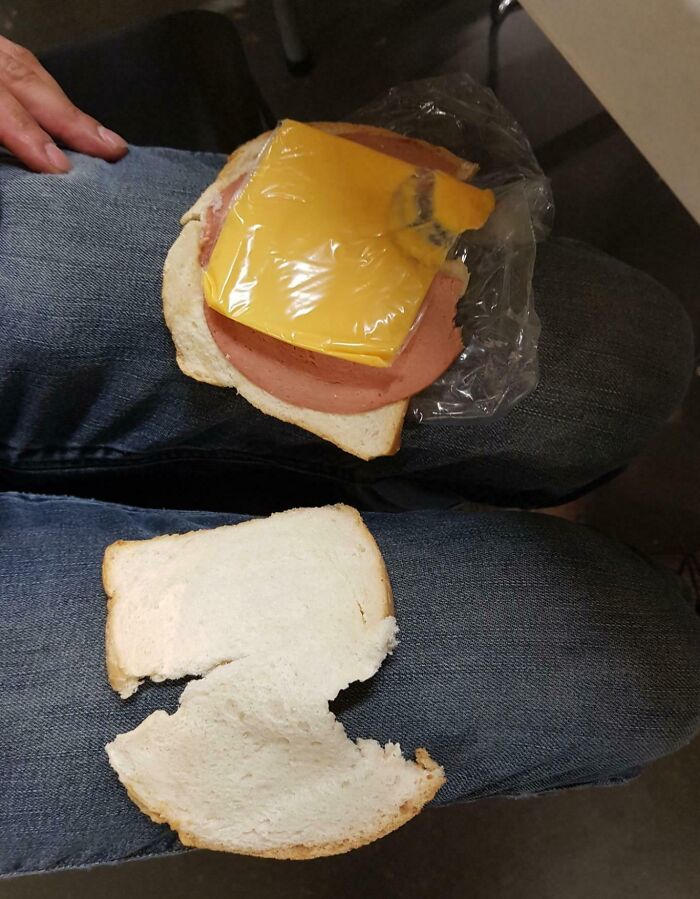 A disappointing sandwich with bologna and unopened cheese on someone's lap.