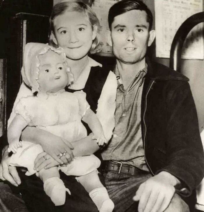 Vintage photo of a couple holding a doll, creating an unsettling atmosphere.