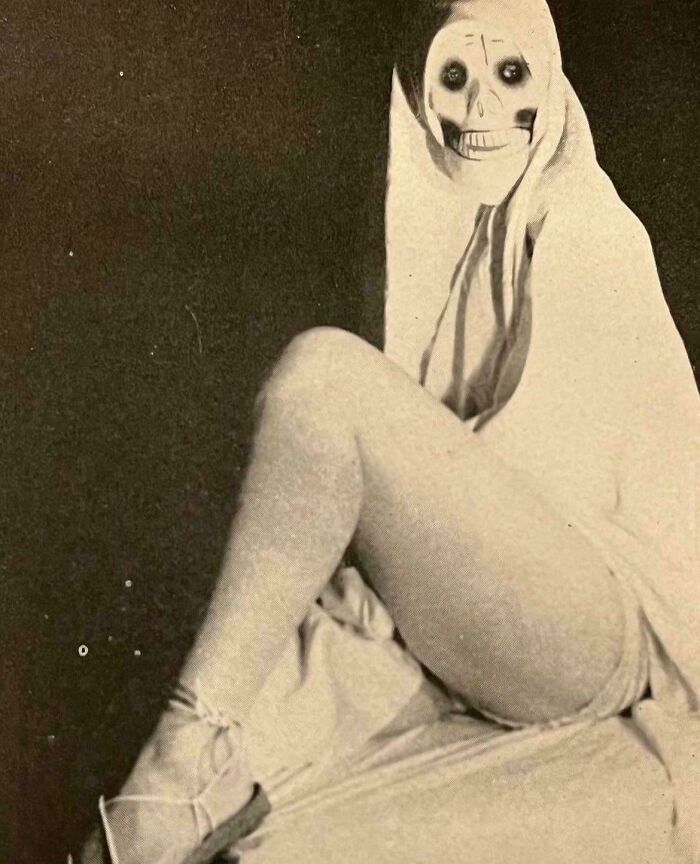 A person in skeletal makeup poses in unsettling vintage attire, creating a haunting atmosphere.