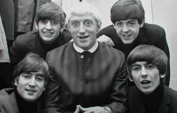 A group photo from the past with five smiling individuals in classic suits, capturing an unsettling moment.