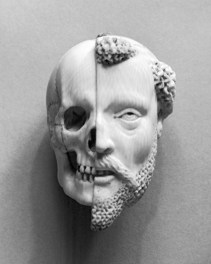 Vintage sculpture depicting a face split between a human and a skull, showcasing unsettling art from the past.