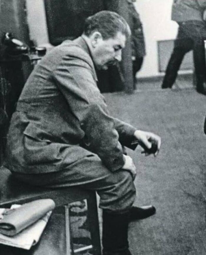 A man in a uniform sits thoughtfully on a bench, holding a small object, creating an unsettling atmosphere.