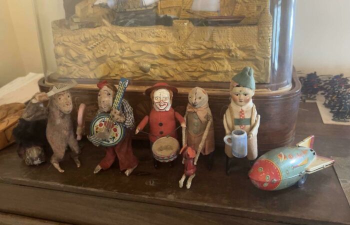 Unsettling vintage toys on a shelf, including figurines and a retro spaceship.