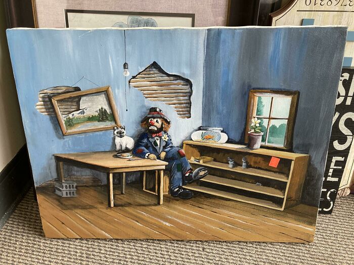 Painting of a sad clown in a sparse room with a cat and broken walls, creating an unsettling atmosphere.