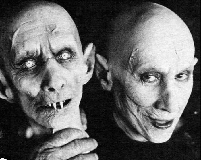 Vintage unsettling photo of two eerie figures with pale skin and sharp features.