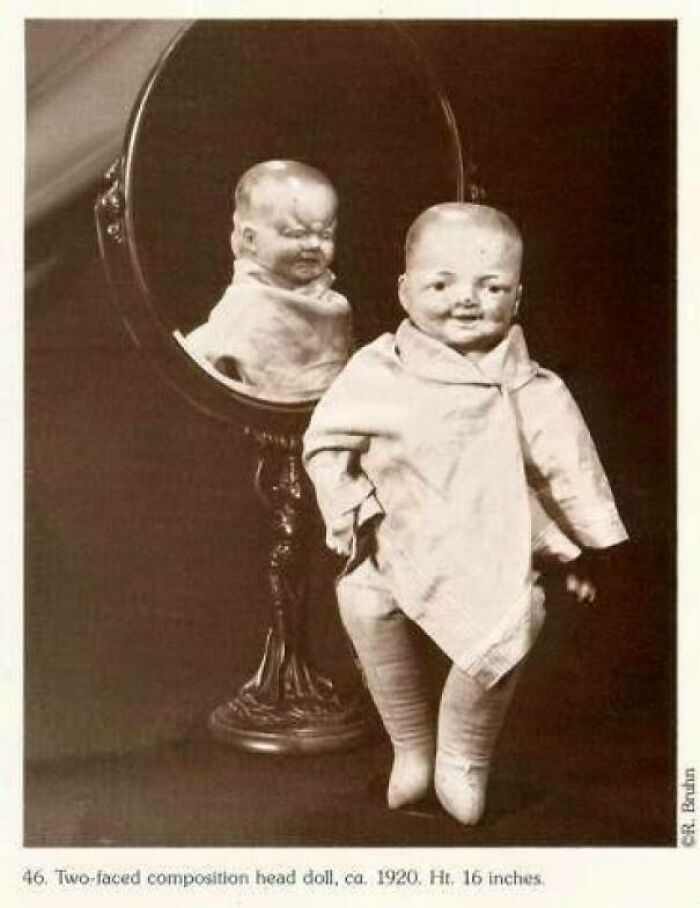 Two-faced vintage doll from the past, reflected in a mirror, looks unsettling and eerie.