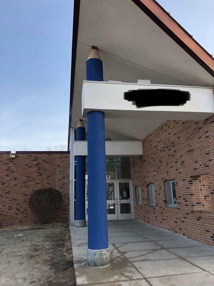 Entrance of an American school with pencil-shaped columns and brick walls.