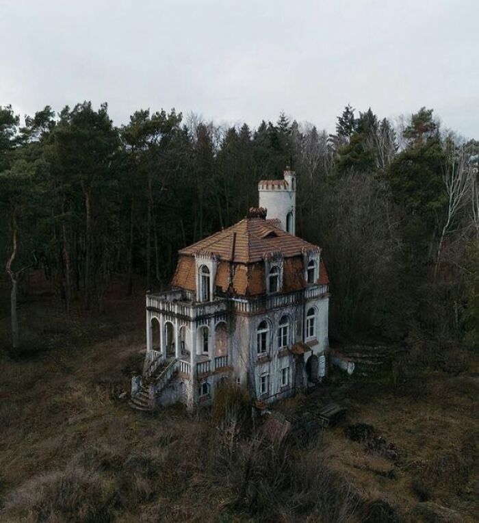 Old, unsettling house amidst a forest, showcasing eerie past architecture.