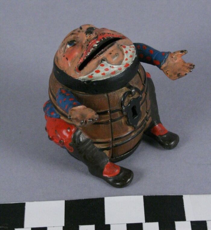 Unsettling vintage toy resembling a humanoid figure with a barrel body and painted features.