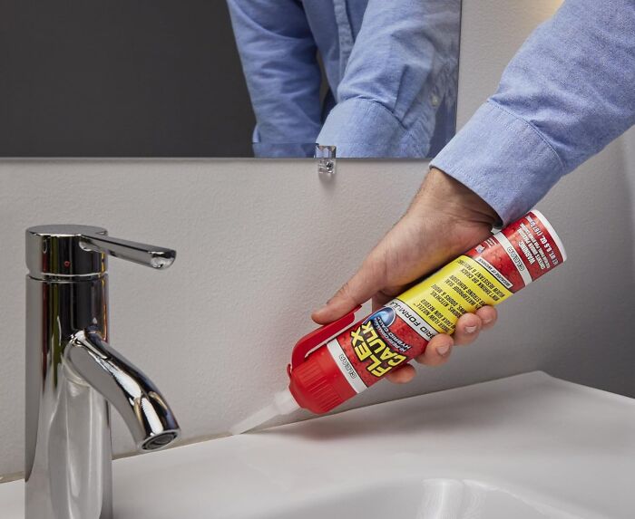 Person applying sealant to a bathroom sink edge, ensuring a proper seal and finish.