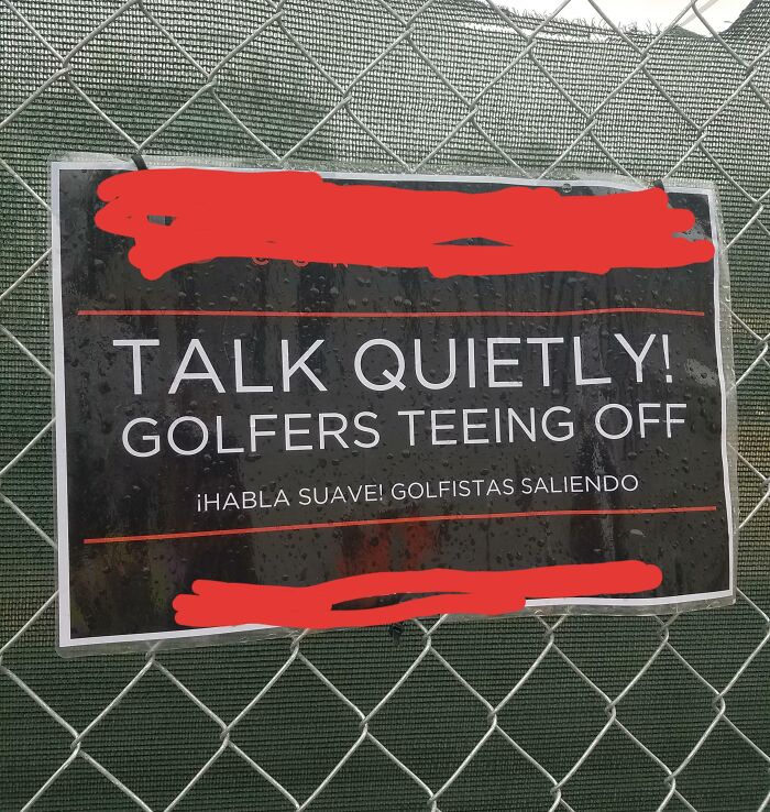 Sign on a fence reads "Talk Quietly! Golfers Teeing Off." Funny image of rich people's indulgences.