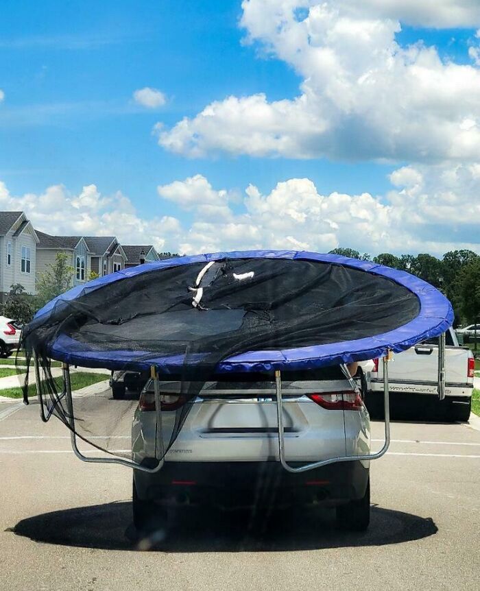 Car transporting large trampoline, rear view obstructed, illustrating a challenging day.