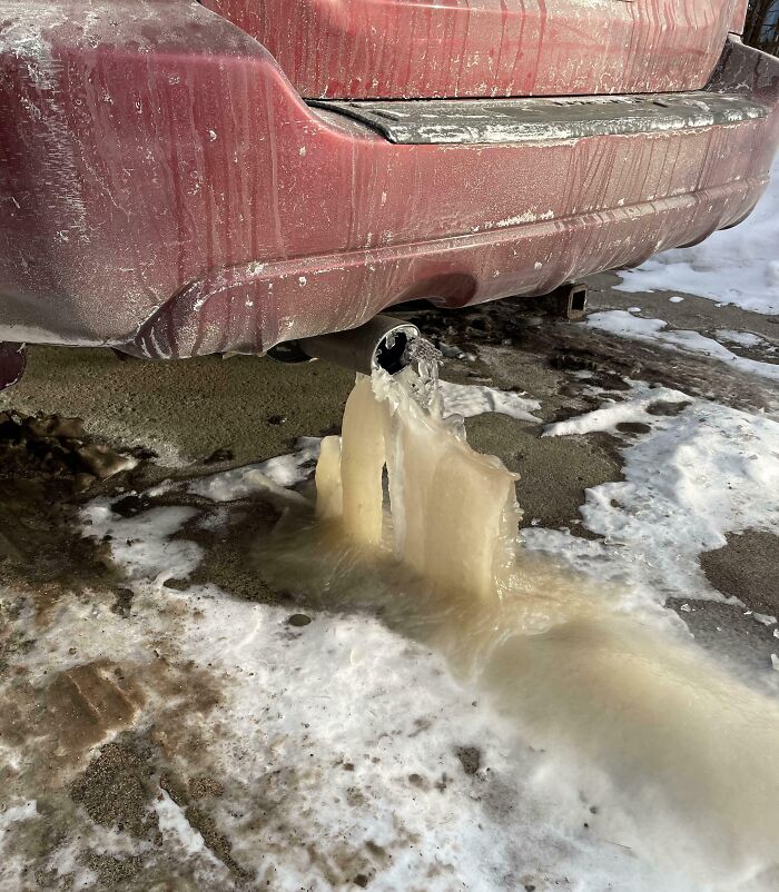Frozen car exhaust with icicles beneath red vehicle, highlighting a worse day scenario.