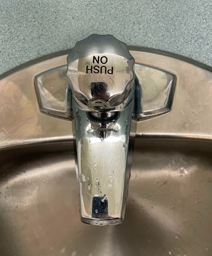 Backwards "push" label on a shiny bathroom faucet.