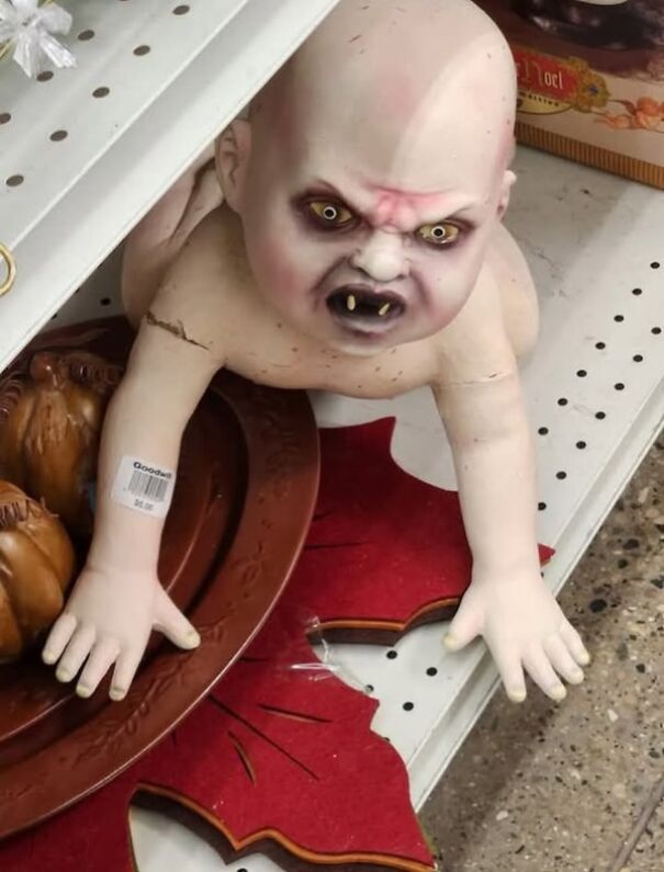 Strange thrift store find: a doll with vampire features, displayed on a store shelf.
