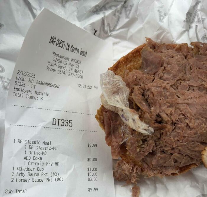 Disgusting discovery in food: an unpleasant item on a sandwich next to a restaurant receipt.