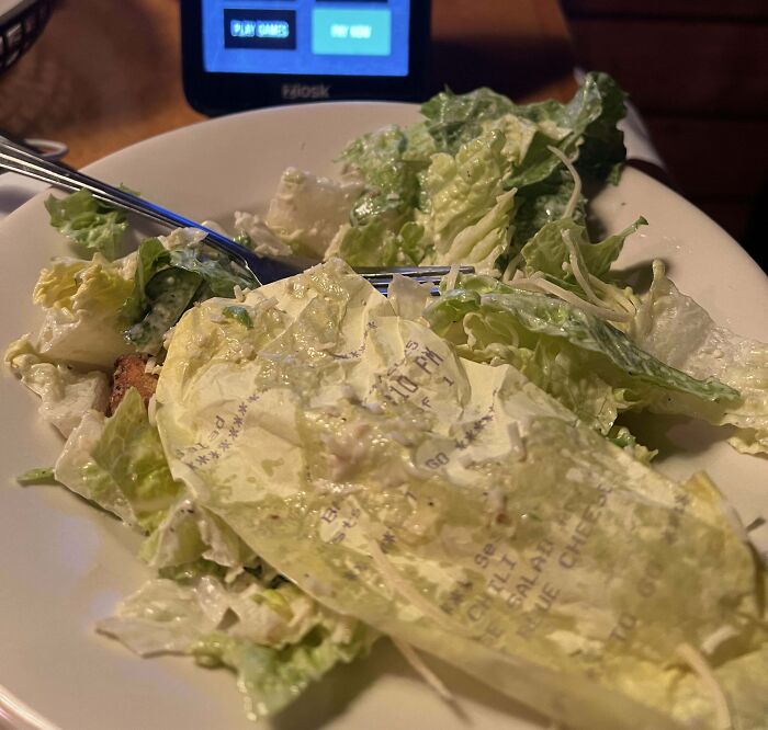 Salad with an unexpected receipt mixed in, highlighting a disgusting food experience.
