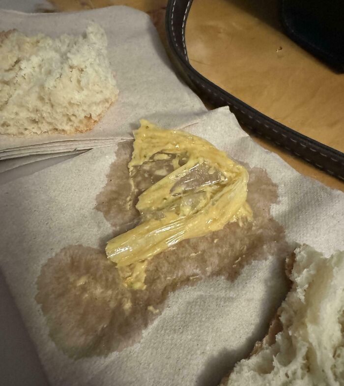 Disgusting surprise in sandwich with clear wrapper found under mustard on a napkin.