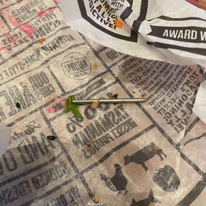 Disgusting surprise found in food wrapper, showing a metal object among food remnants.