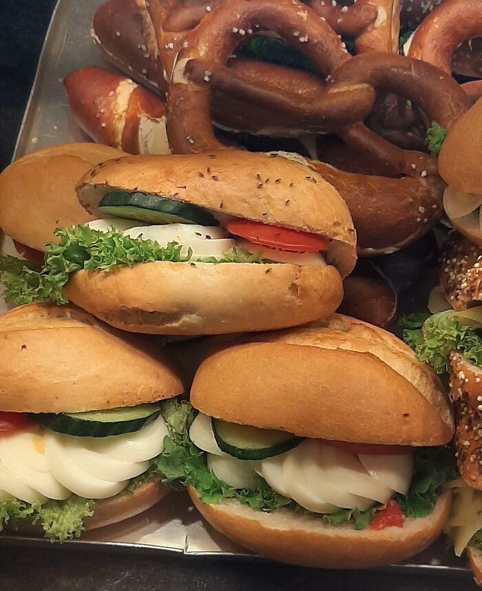 Assorted buns with lettuce, eggs, cucumbers, and pretzels on a tray, an example of unexpected food surprises.