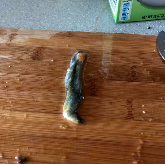 Disgusting discovery on a cutting board, unexpected item in food preparation.