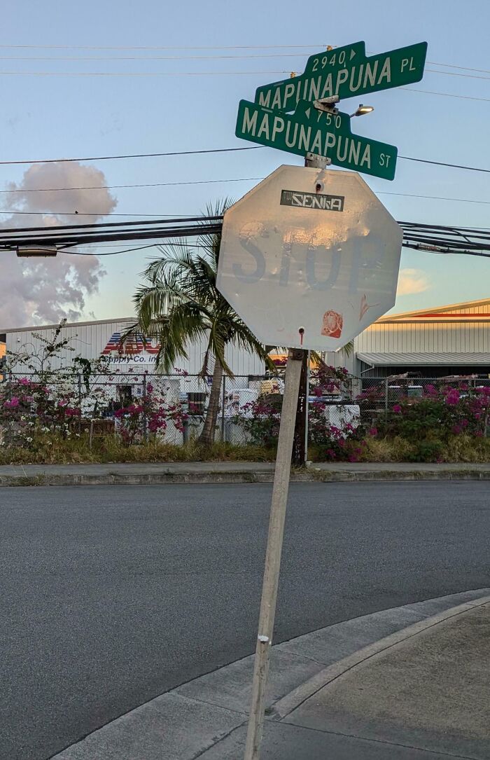 Worn-down stop sign at street intersection, showing effects of time with faded lettering and bent post.