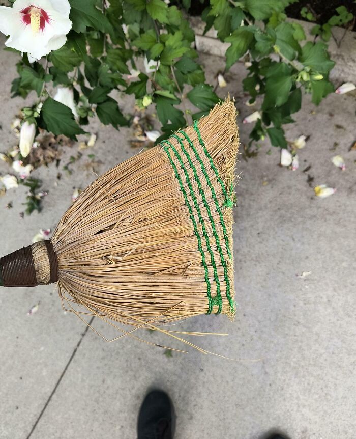 Escoba desgastada sobre el suelo de concreto, mostrando el efecto del tiempo en sus cerdas gruesas.
