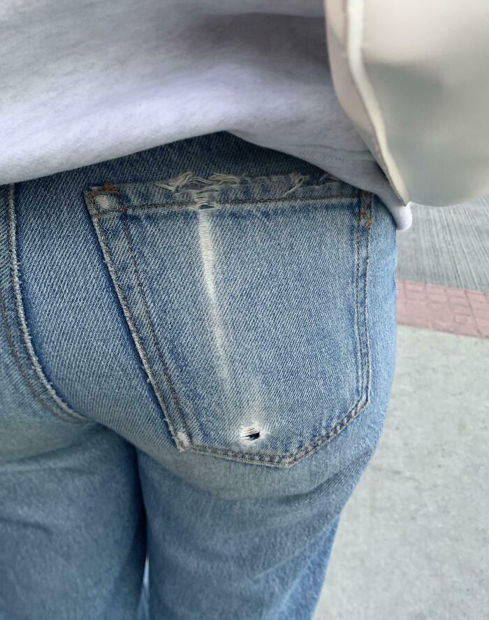 Worn denim jeans with a frayed pocket and small hole, showcasing belongings getting worn-down by time.