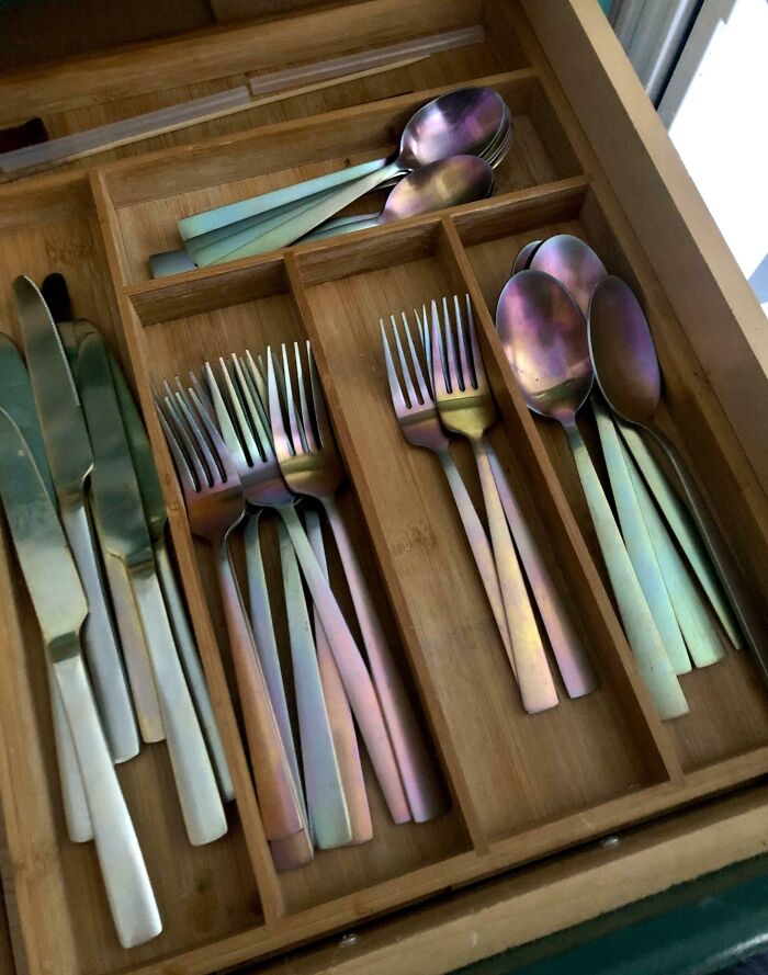 Cubiertos desgastados en un cajón de madera.