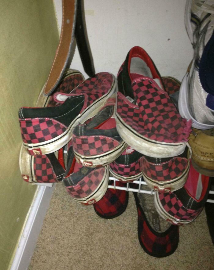 Worn-down checkered shoes stacked on a wire shelf, showcasing time's impact on people's belongings.
