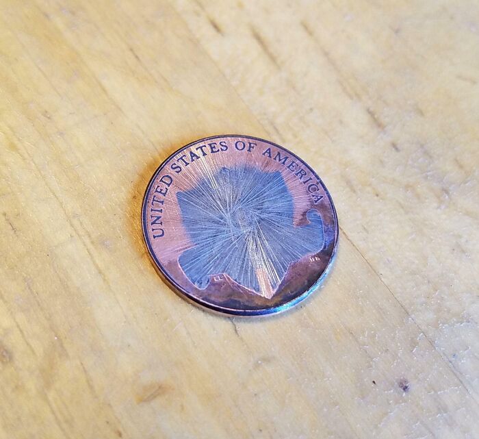 Worn-down coin from the United States of America on a wooden surface, illustrating the effects of time on belongings.