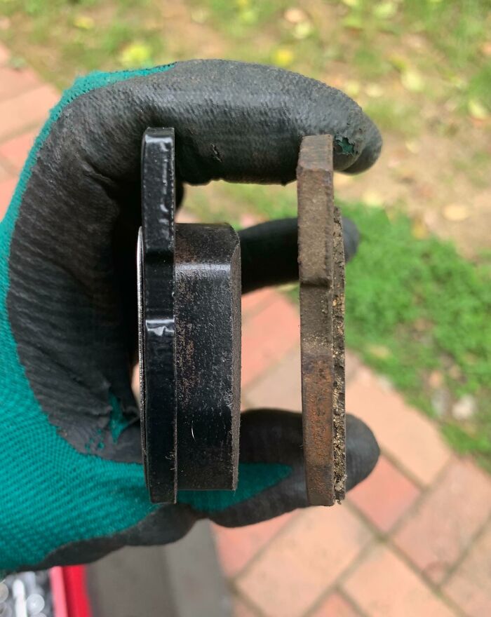 Worn-down brake pad comparison highlighting the effects of time on belongings, held in a gloved hand.