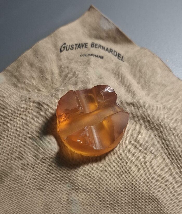 Worn-down violin rosin on a Gustave Bernardel cloth, showcasing the effects of time on belongings.