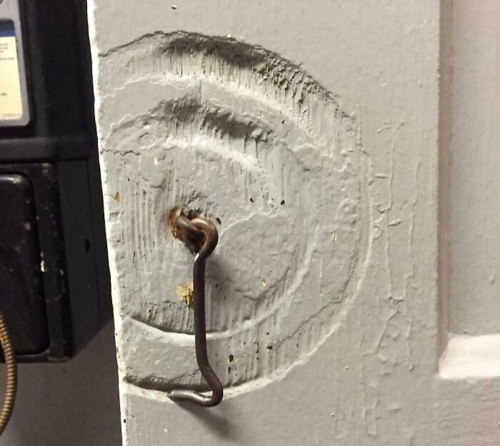 Clavo oxidado desgastando una puerta de madera con el tiempo.