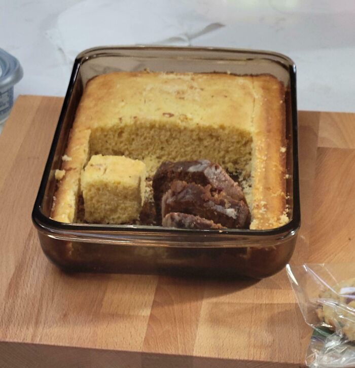 Unusual cake with a large piece missing, placed on a wooden counter, depicting in-law troubles.