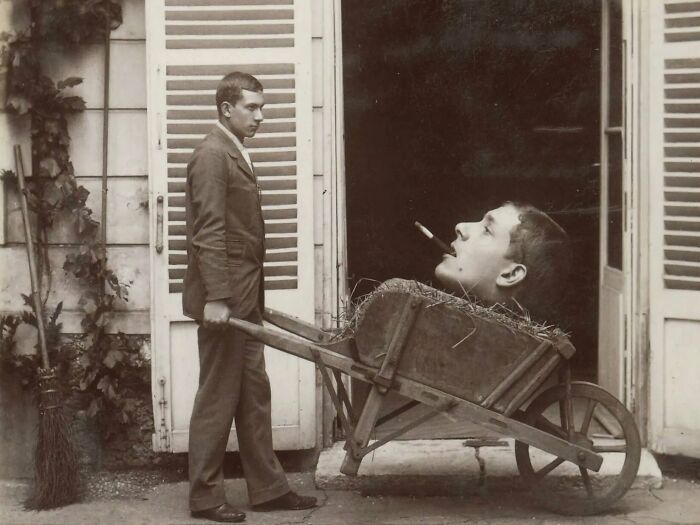 Man with wheelbarrow carrying giant head, creating an unsettling past scene.