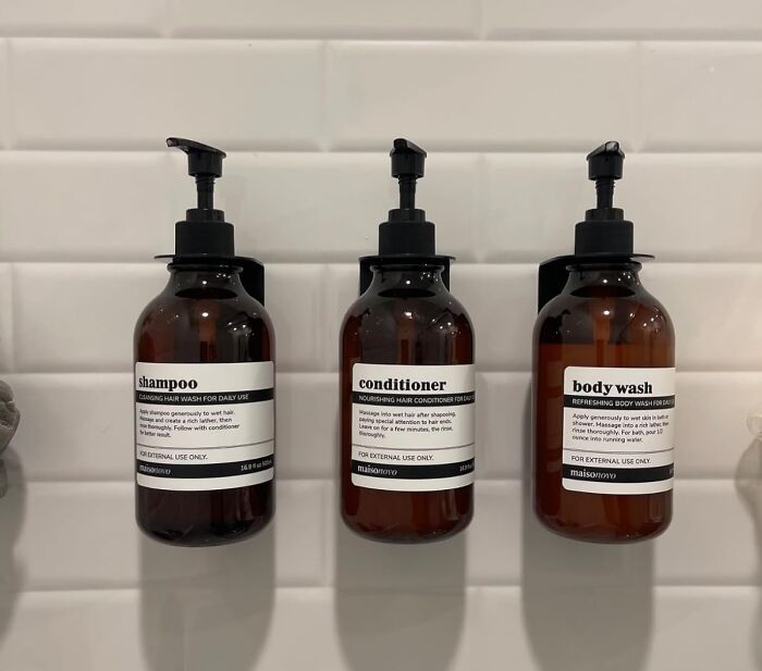 Brown shampoo, conditioner, and body wash bottles on a tiled wall; essentials for handling Costco a*******n.