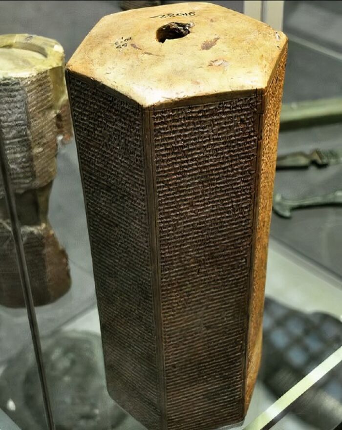 Ancient civilizations' secrets inscribed on a hexagonal stone artifact in a museum display.