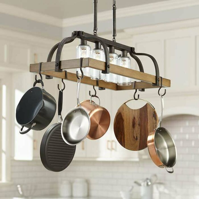 Rustic pot rack hanging with various pans and cutting board in a kitchen, illustrating poorly-aging interior design trends.
